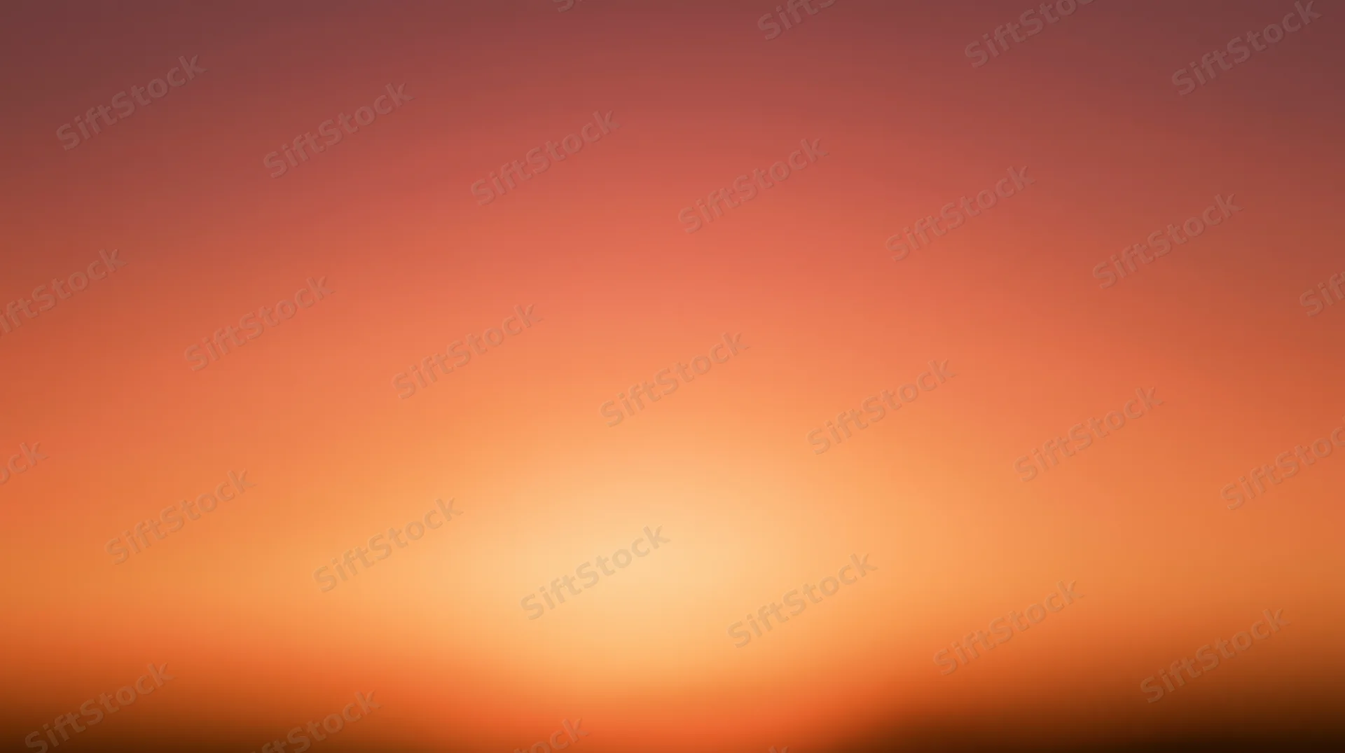 Smooth gradient of orange and pink hues across a blurred sky at dusk