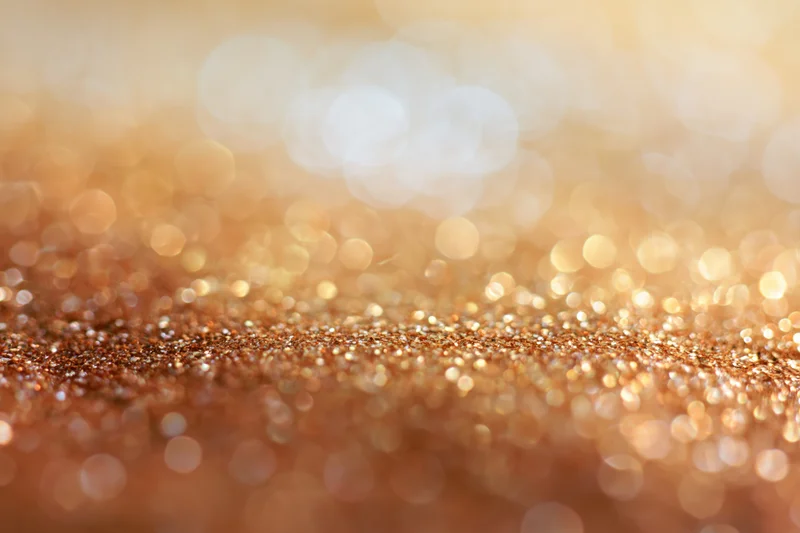Golden glitter surface with soft bokeh lights in the background