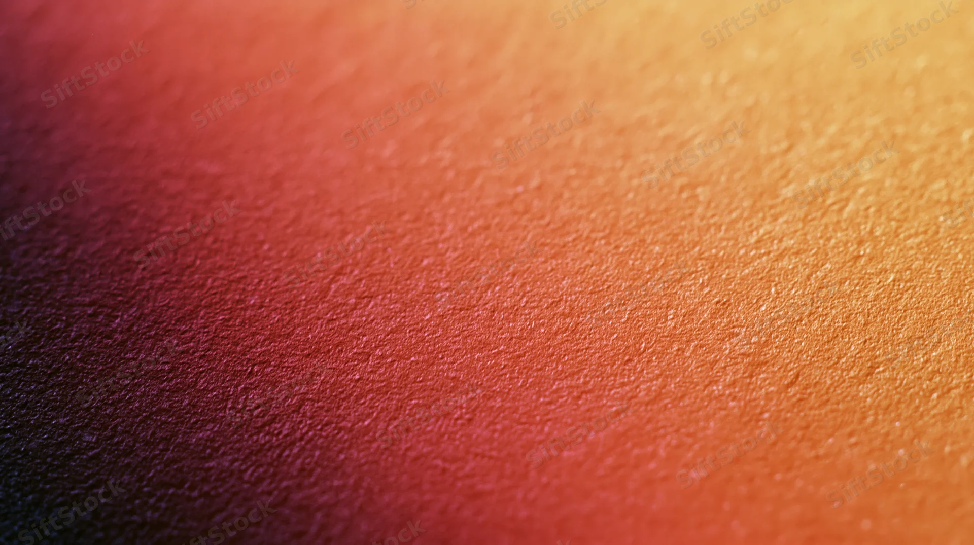 Close-up of a grainy textured surface with a warm orange to red gradient