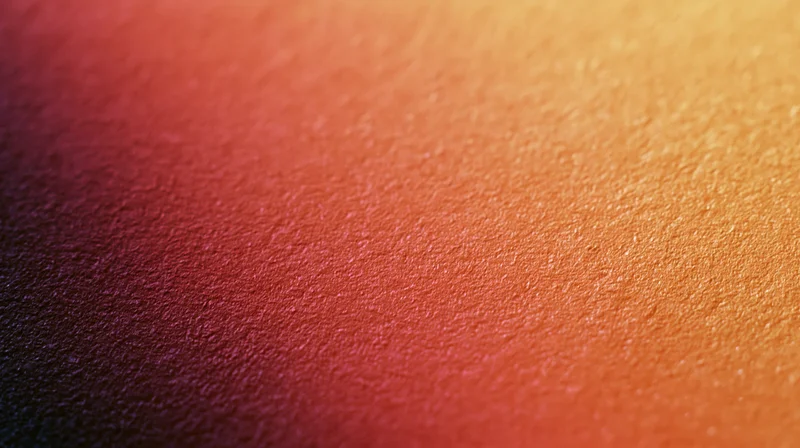 Close-up of a grainy textured surface with a warm orange to red gradient