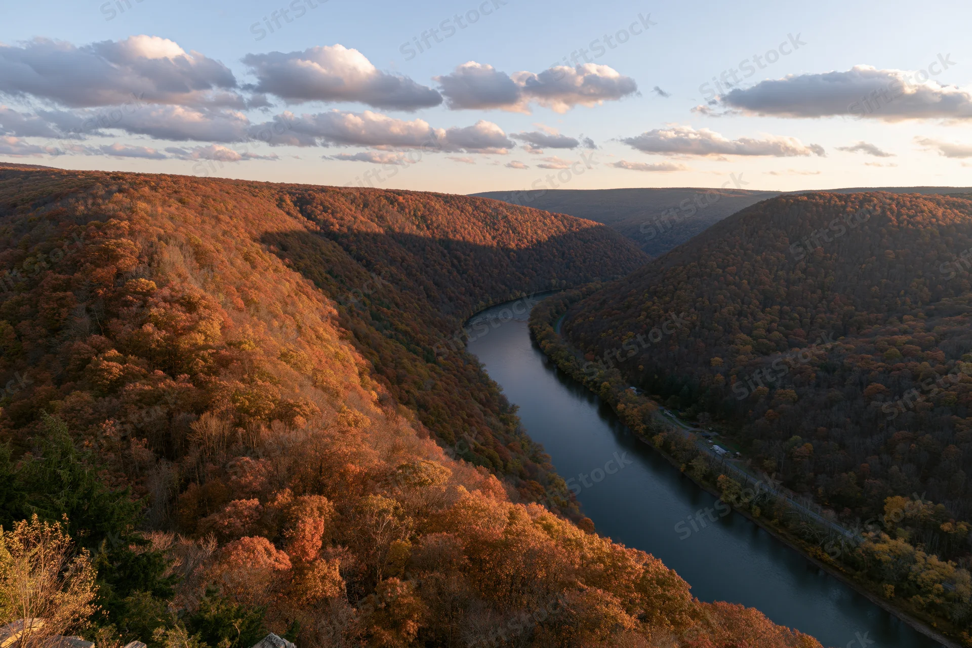 Aerial view of a winding river through a forested valley in autumn