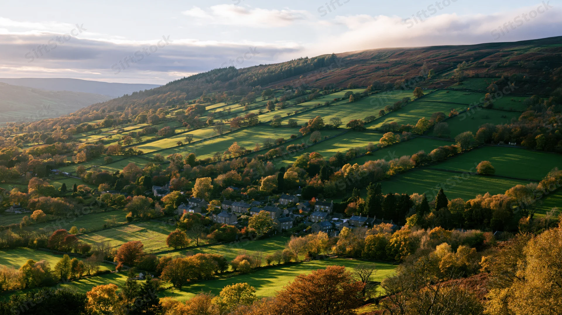 Aerial view of an english countryside valley in autumn with rolling hills, green fields, and a small village nestled among trees and hedgerows