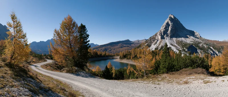 Winding gravel path through alpine autumn landscape with lake and mountain peak