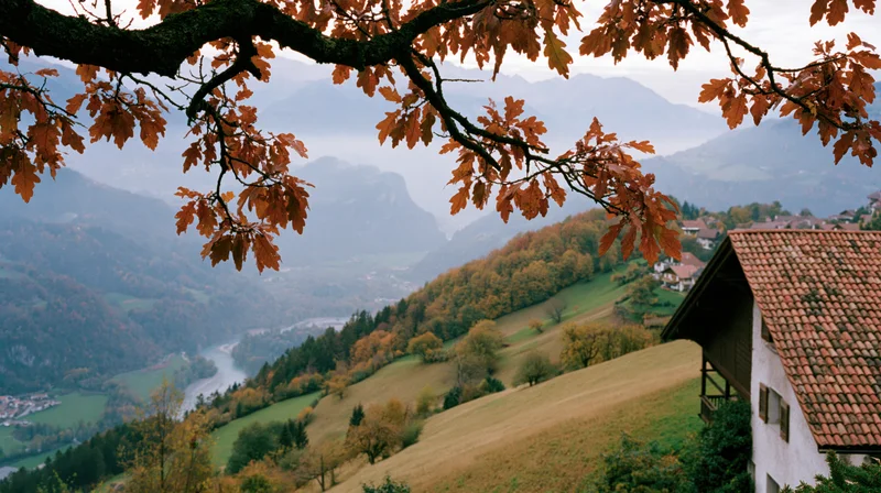 Autumnal alpine landscape with village and mountains framed by tree branches