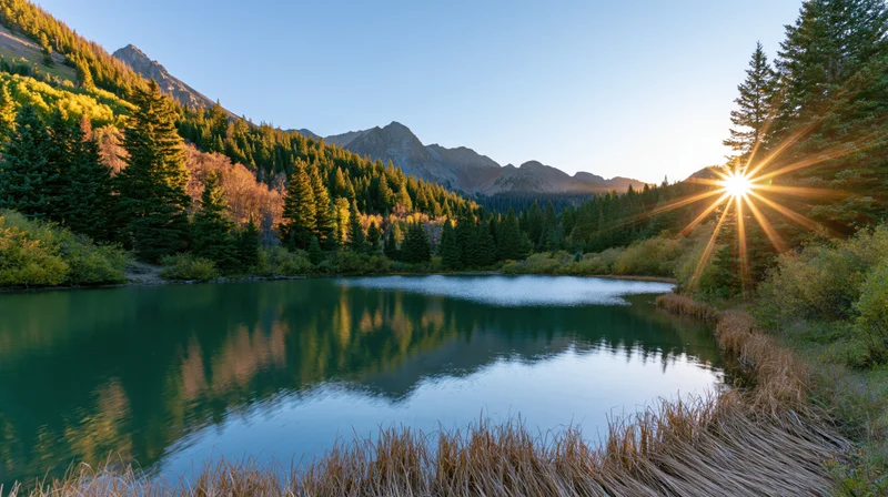 Alpine lake reflecting mountains and trees at sunrise in a forested valley