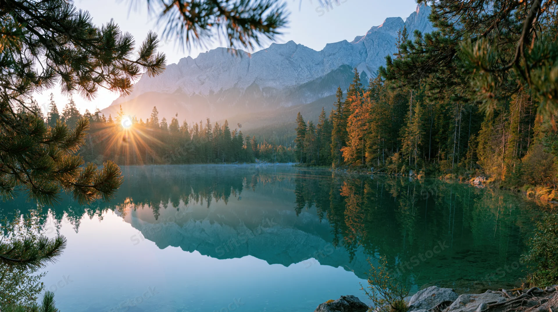 Alpine lake reflecting mountains and forest at sunrise with still water and pine branches framing the view