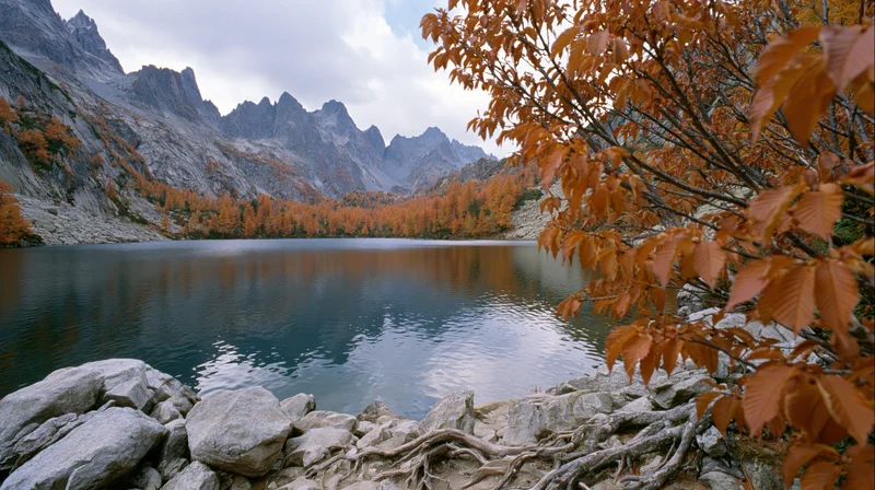Alpine lake reflecting jagged rocky peaks surrounded by autumn foliage and trees