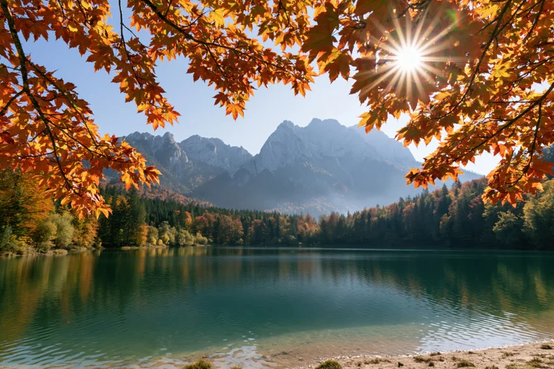 Alpine lake reflecting mountains and autumn trees under bright sunlight