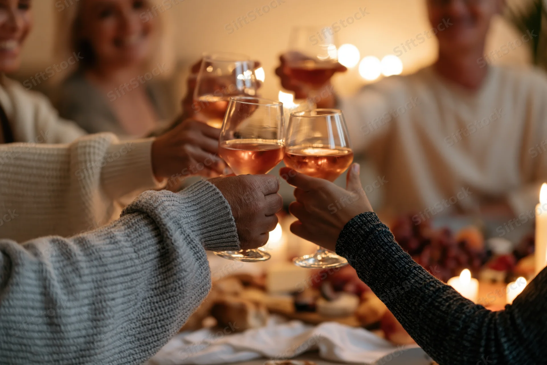 Friends toasting with wine glasses at a dinner table lit by candles