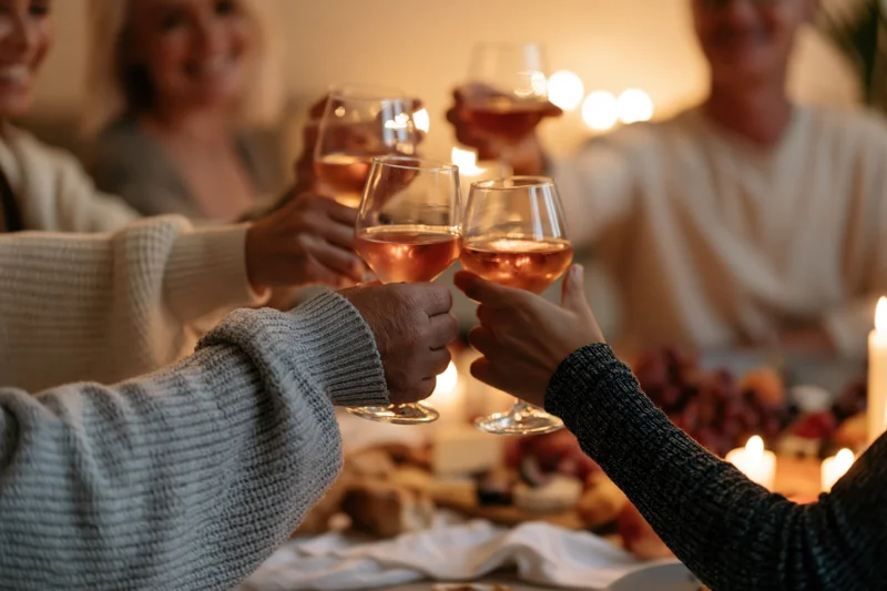 Friends toasting with wine glasses at a dinner table lit by candles