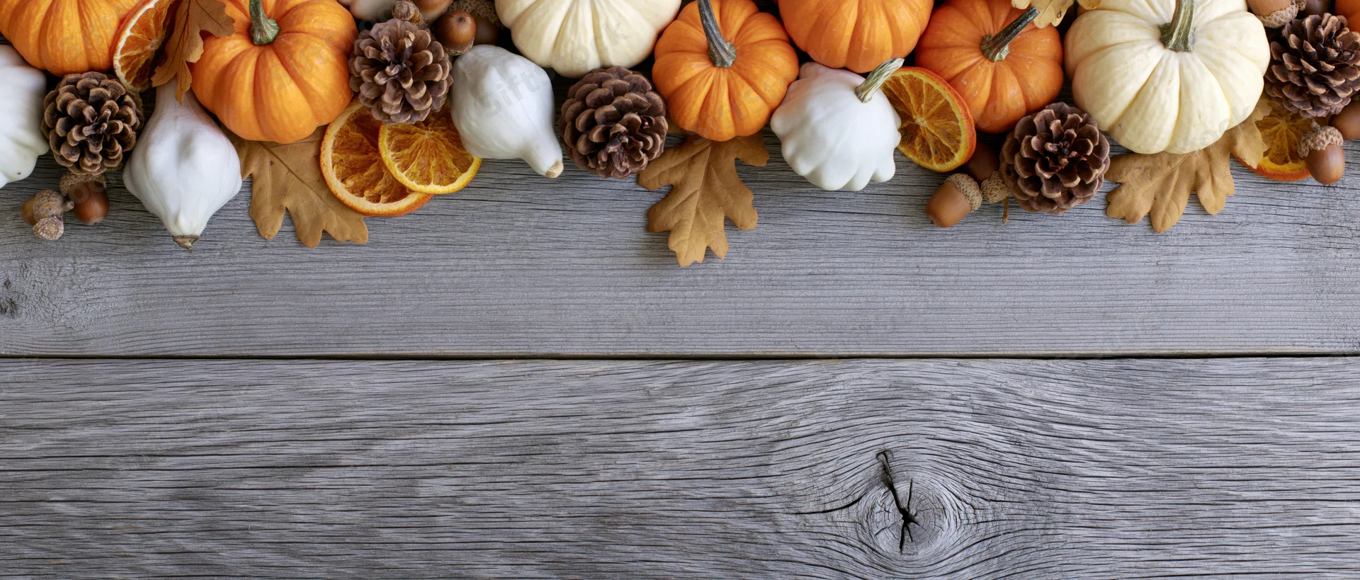 Autumn decorations arranged along the top of a weathered wooden table with copyspace below