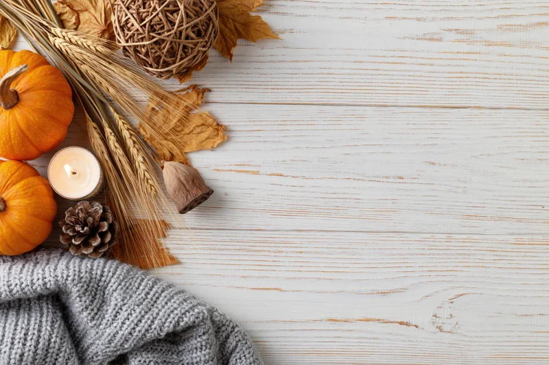 Autumn flat lay with pumpkins, wheat, candle and sweater on white wooden table