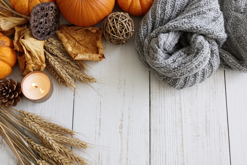 Autumn flat lay with pumpkins, scarf, candle and wheat on white wooden table