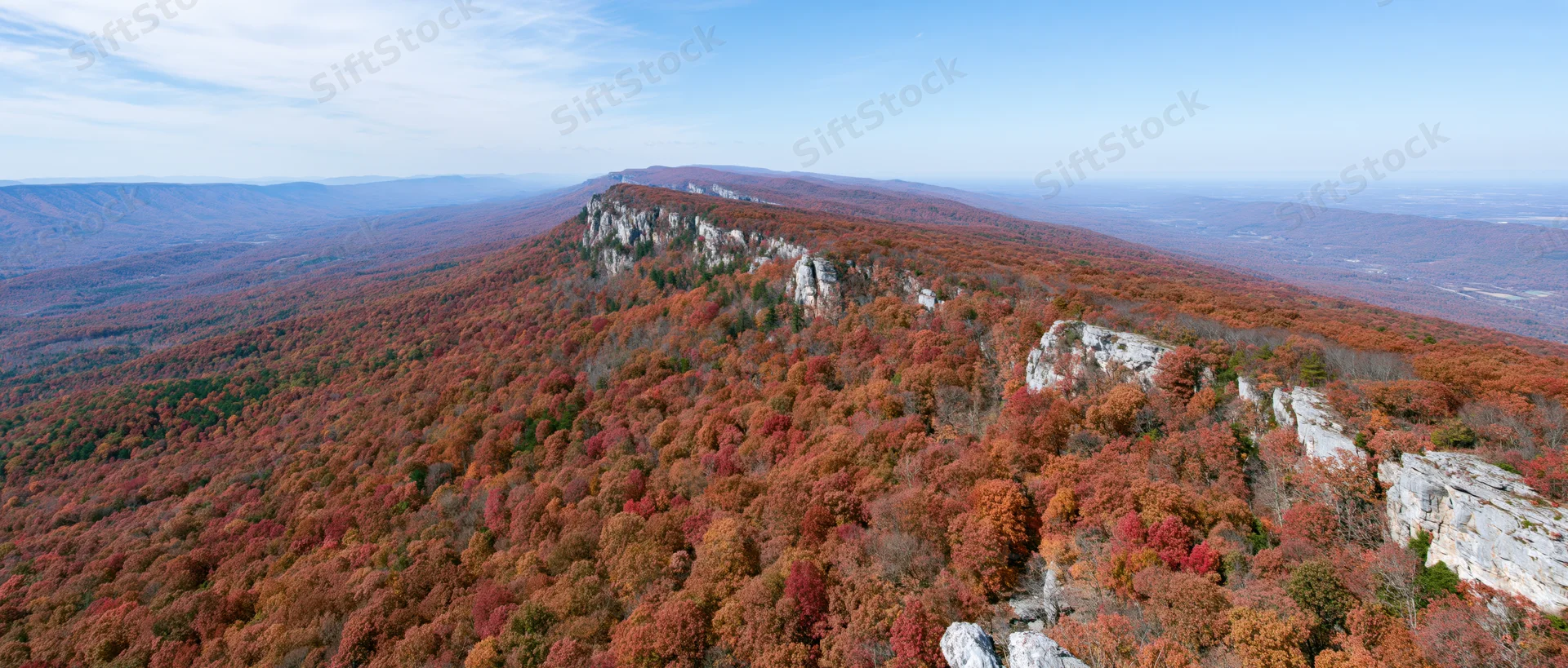 Aerial view of autumn forest covering steep mountain slopes with rocky limestone cliffs