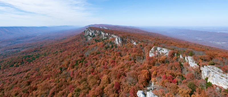 Aerial view of autumn forest covering steep mountain slopes with rocky limestone cliffs