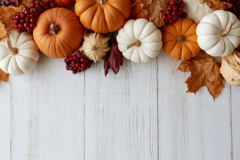 Autumn pumpkins and leaves arranged in a flat lay on a white wooden table