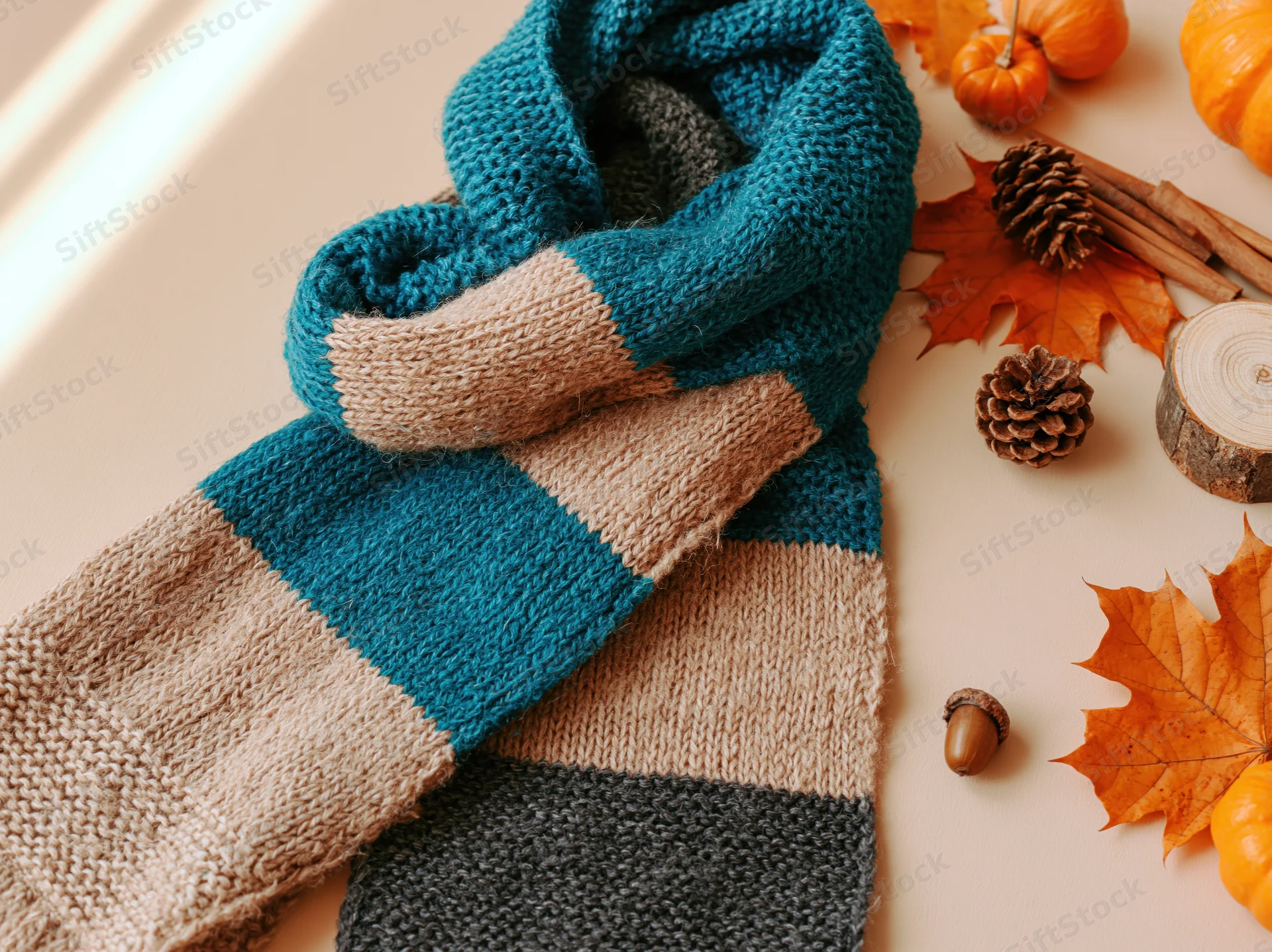 Knitted scarf with autumn decorations arranged on a flat surface