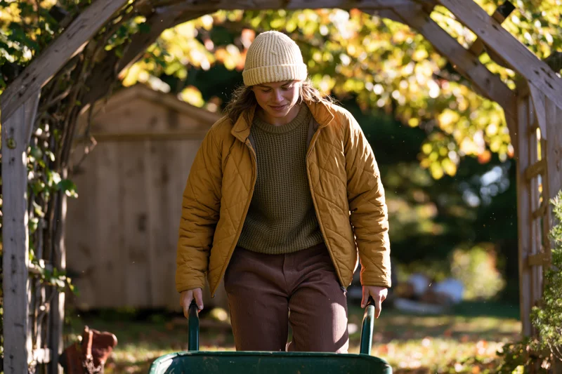 Woman pushing a wheelbarrow through a wooden arbor in a garden during autumn
