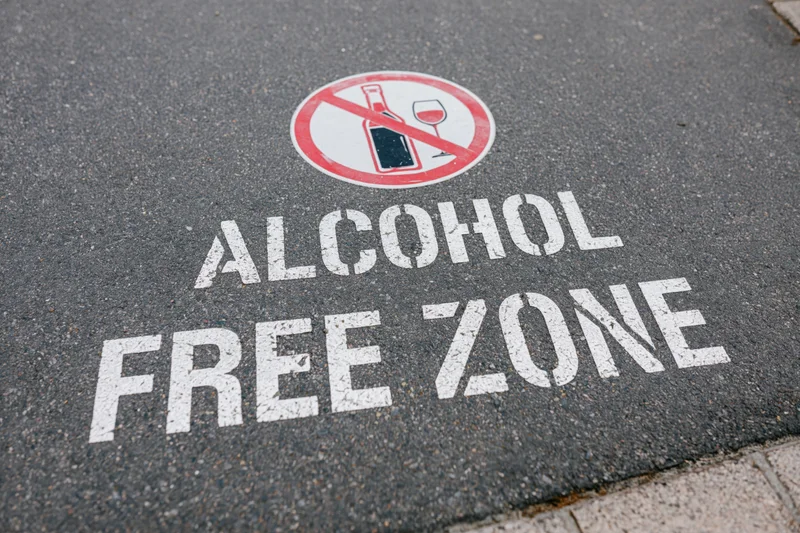Alcohol free zone text stenciled on dark asphalt pavement