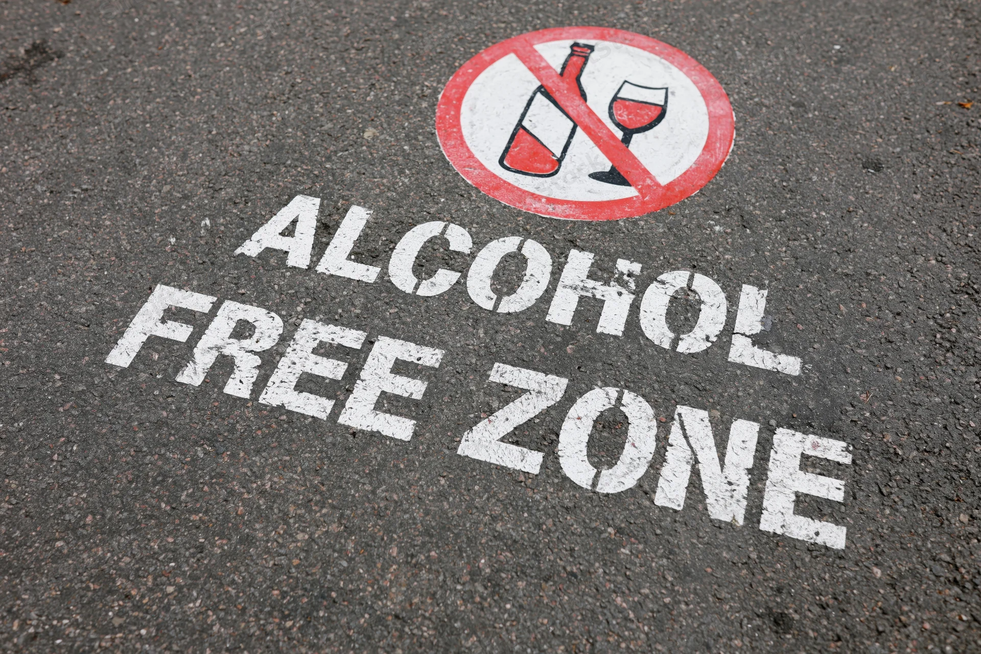 Alcohol free zone text and no alcohol symbol painted on asphalt pavement