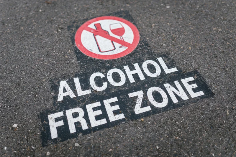 Alcohol free zone text stenciled on dark asphalt pavement