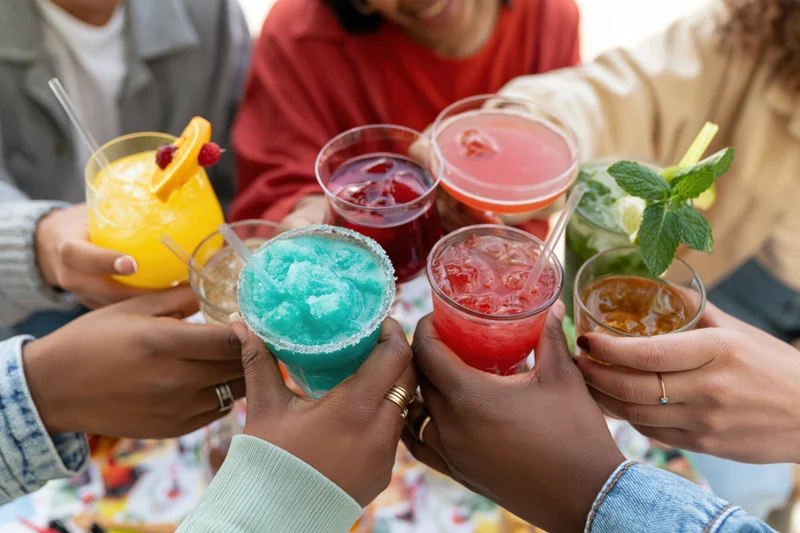 Diverse friends toasting with colorful cocktails at an outdoor gathering