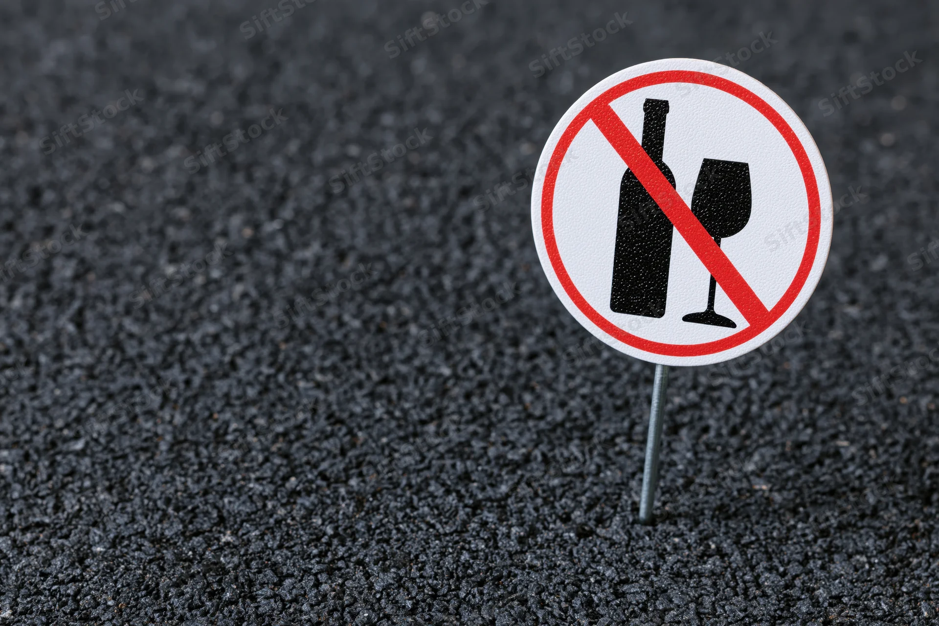 No-alcohol prohibition sign on metal pole in asphalt pavement
