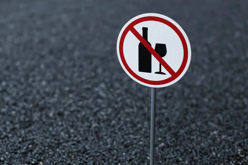 No-alcohol prohibition sign on metal pole in asphalt pavement
