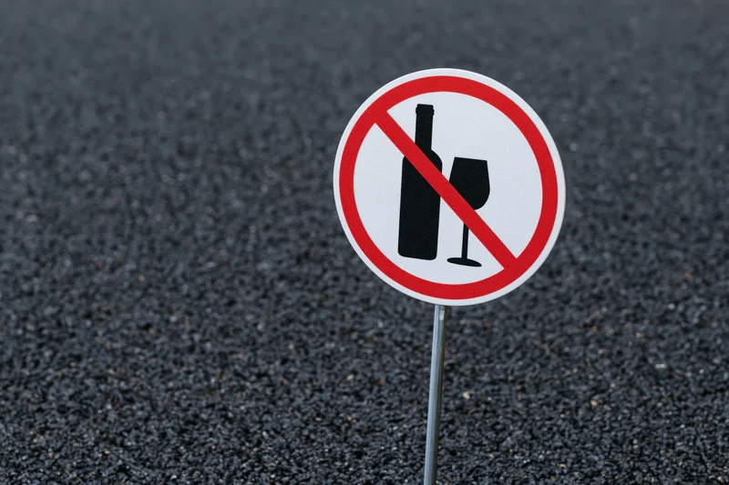 No-alcohol prohibition sign on metal pole in asphalt pavement