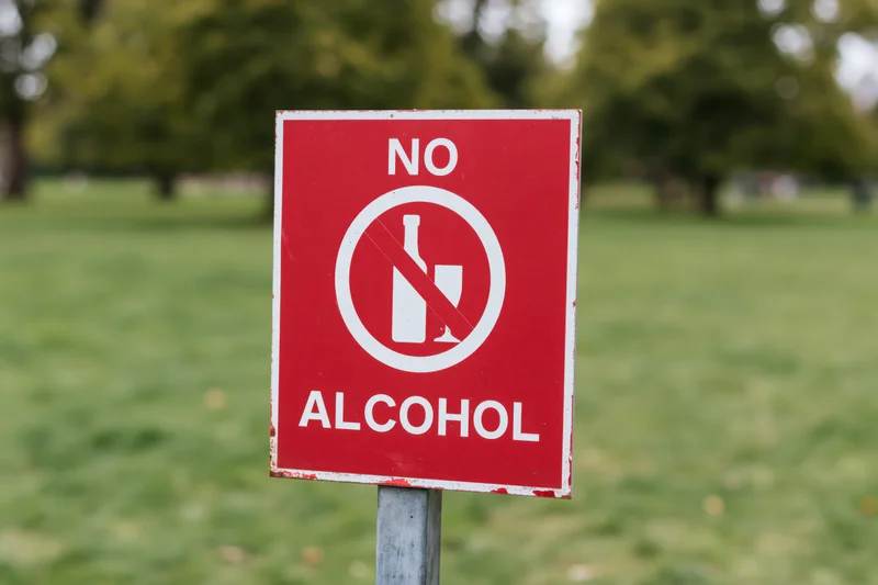 Red prohibition sign forbidding alcohol in a grassy park area