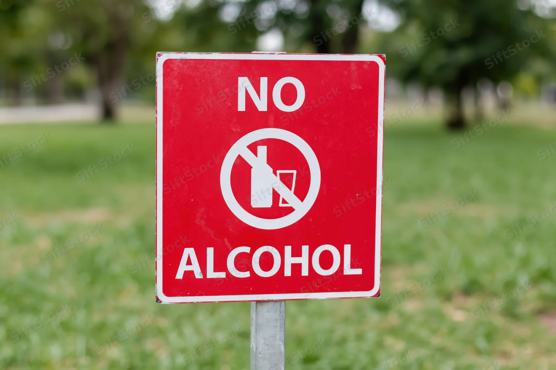 Red prohibition sign forbidding alcohol in a grassy park area