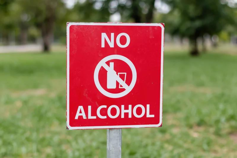 Red prohibition sign forbidding alcohol in a grassy park area