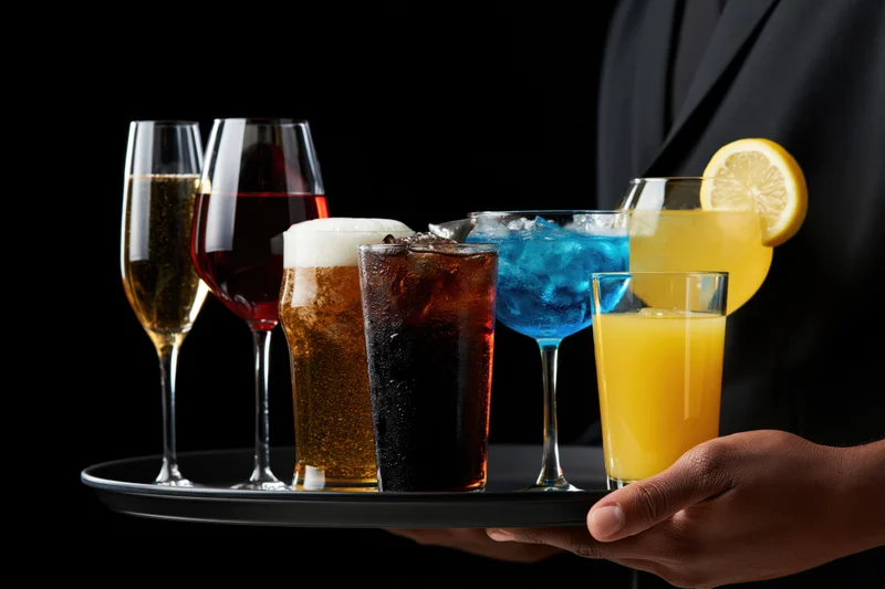 Server holding tray with assorted drinks at shoulder height