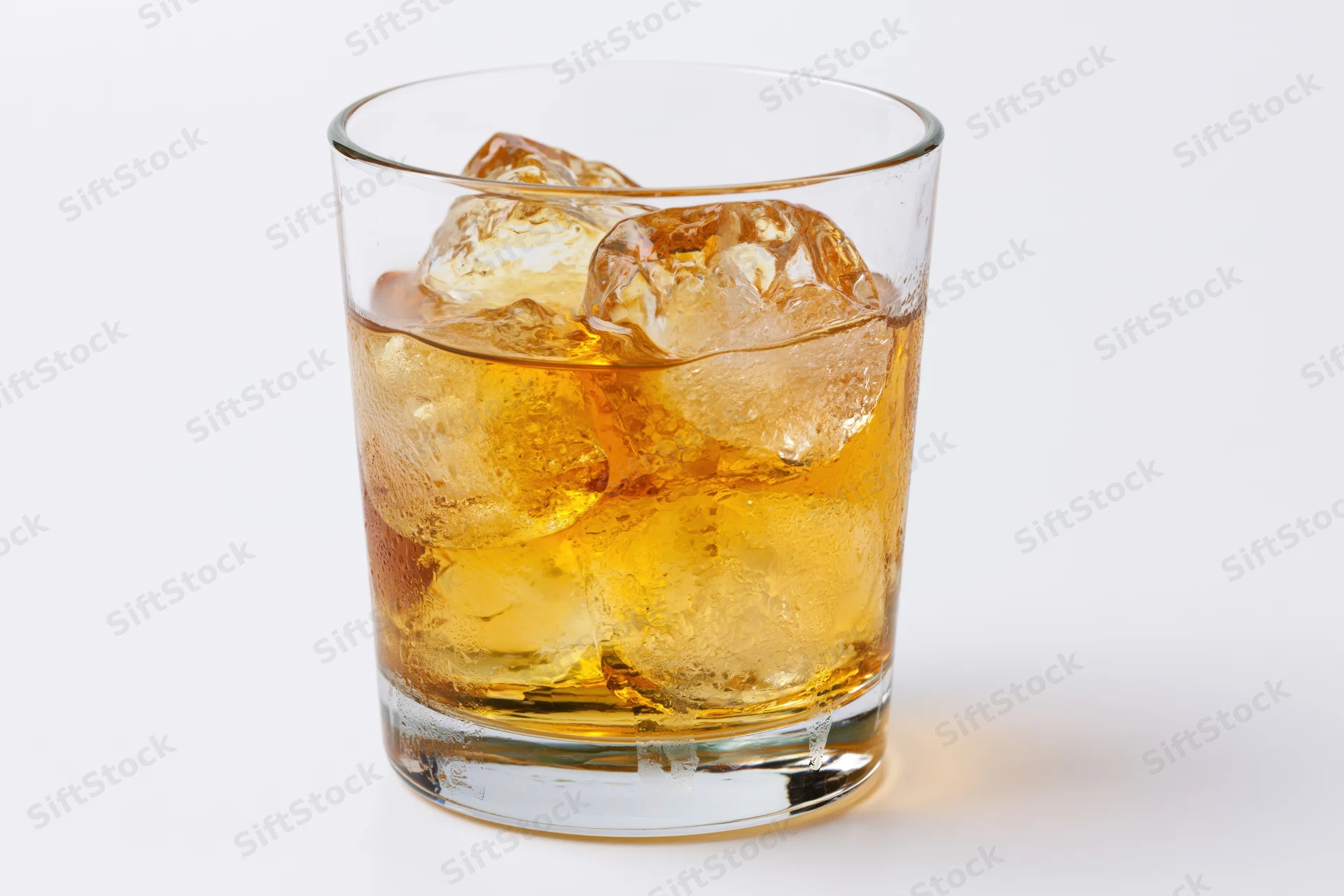 Amber whiskey with ice in a short rocks glass on white background