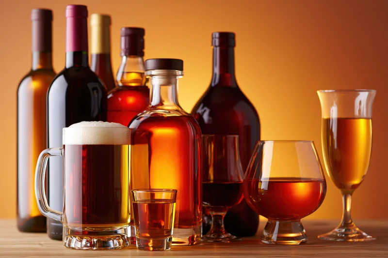 Assorted alcohol bottles and glasses arranged on a wooden surface
