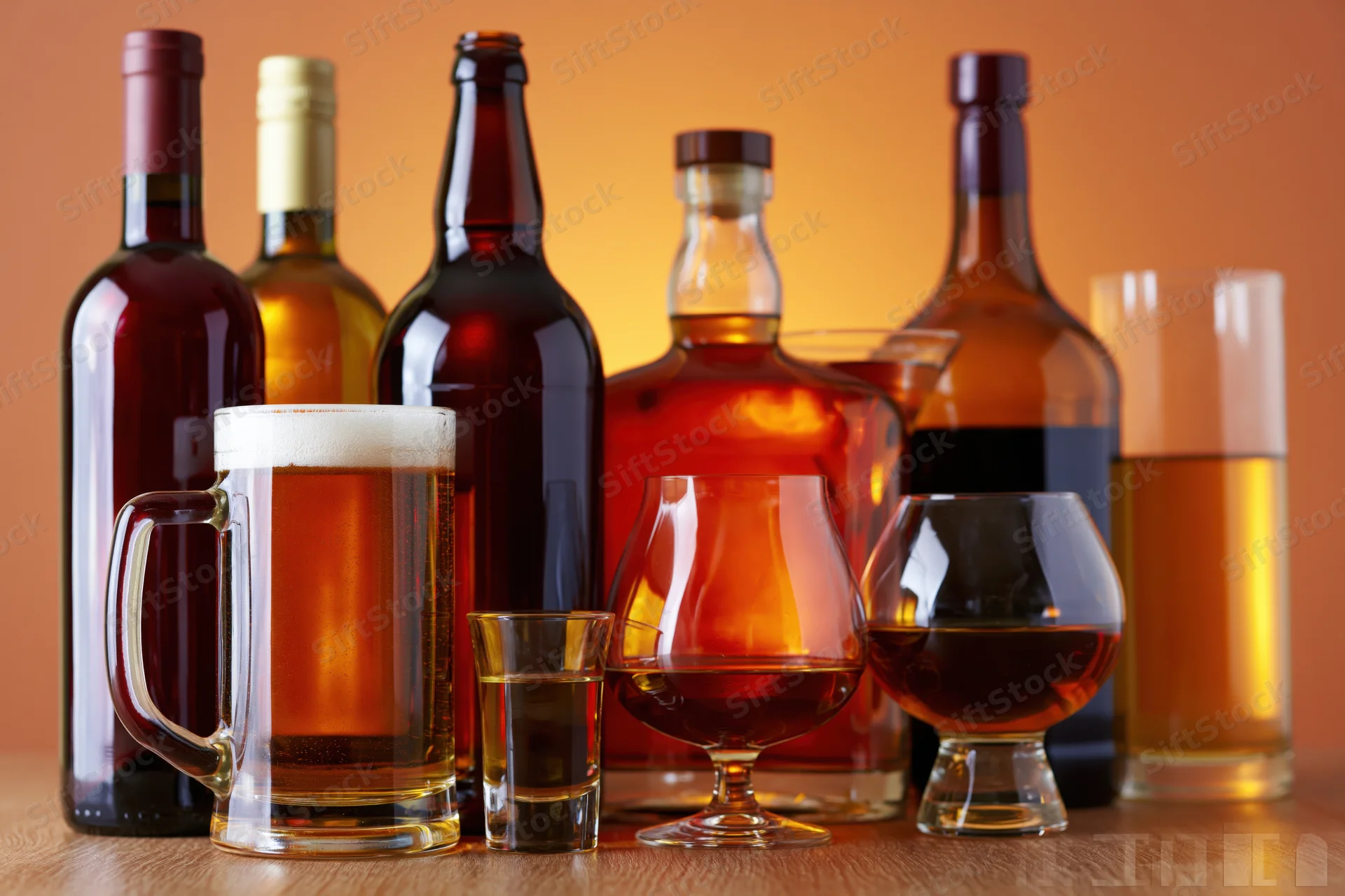 Assorted alcohol bottles and glasses arranged on a wooden surface