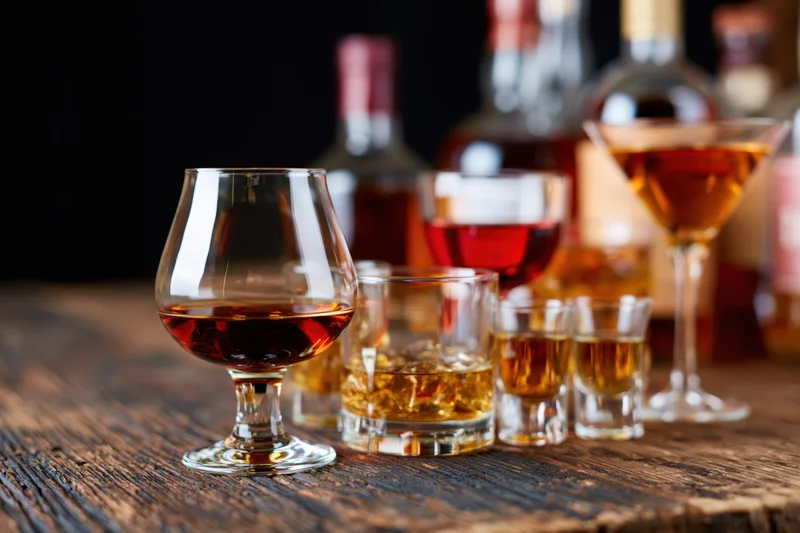 Assorted bar glasses filled with various spirits arranged on a wooden table