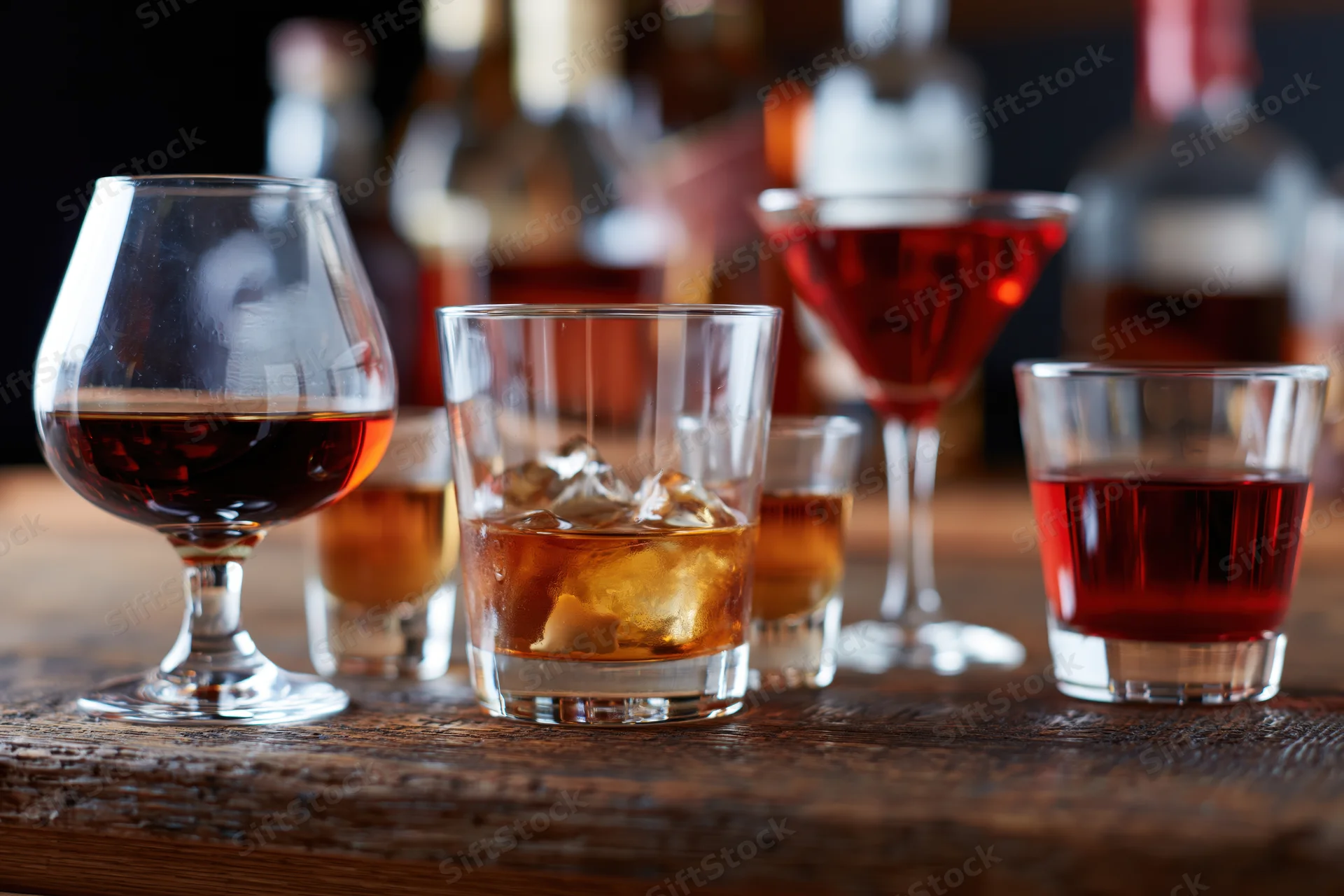 Assorted bar glasses filled with various spirits arranged on a wooden table