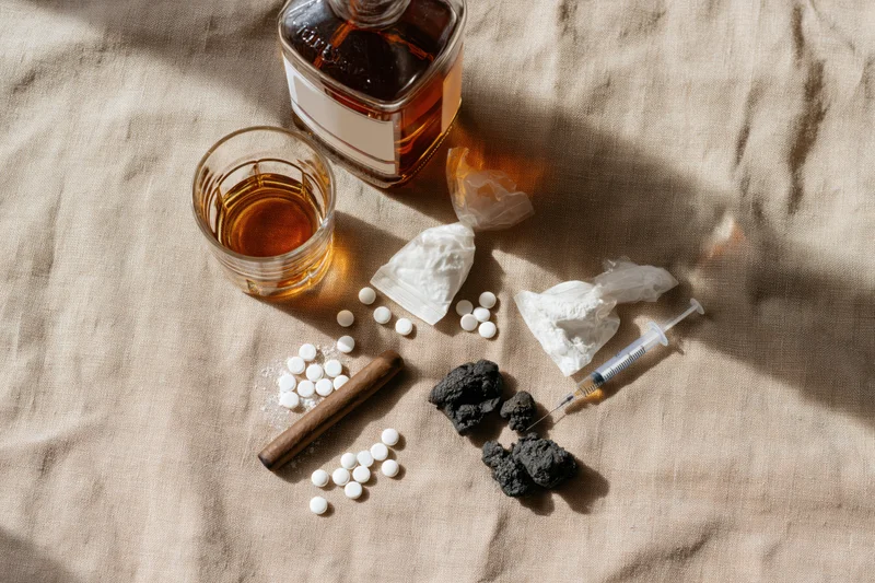 Various addiction-related items arranged on a beige fabric surface in a flat lay composition