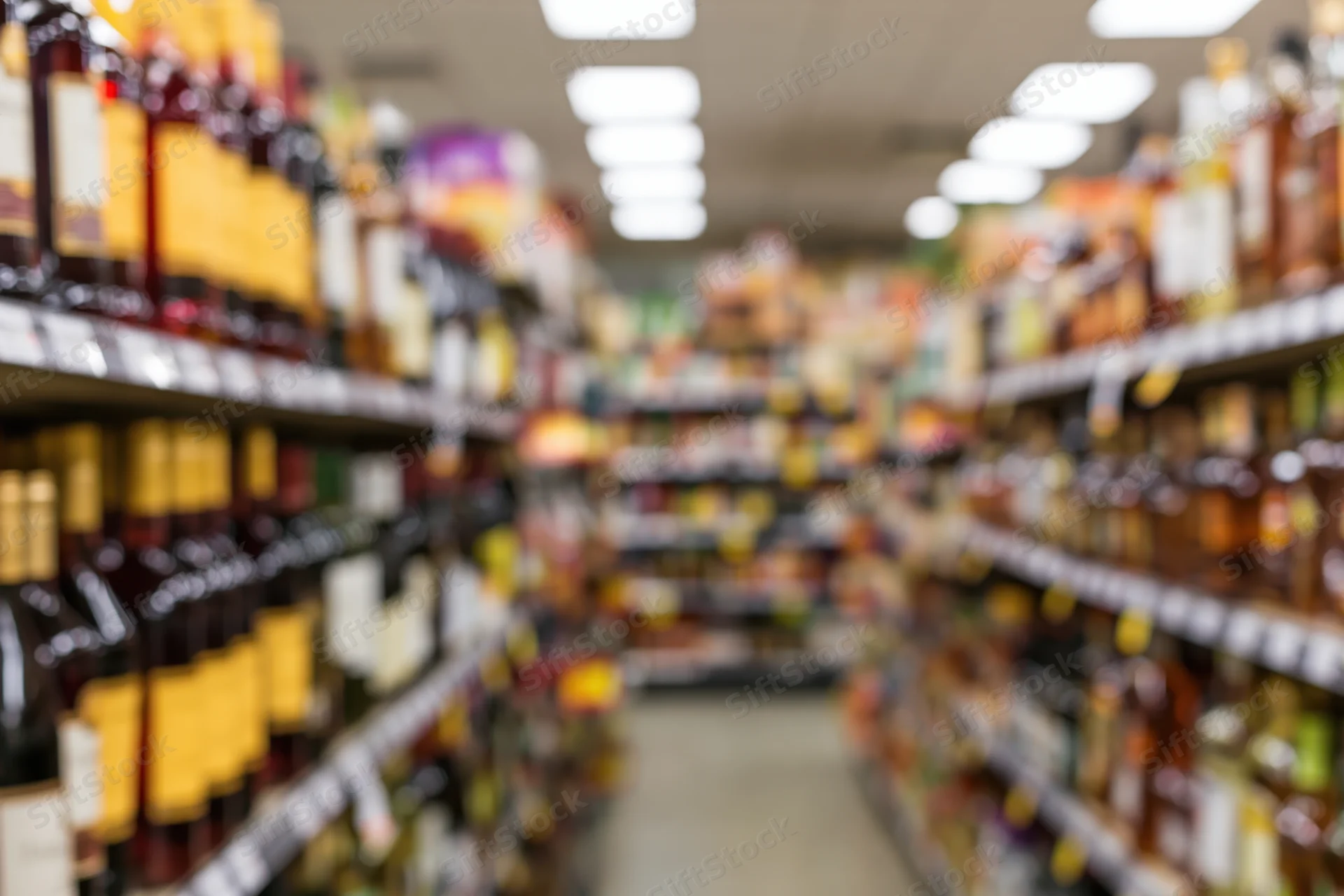 Blurred view of liquor store aisle with tall shelves lined with bottles stretching into the distance