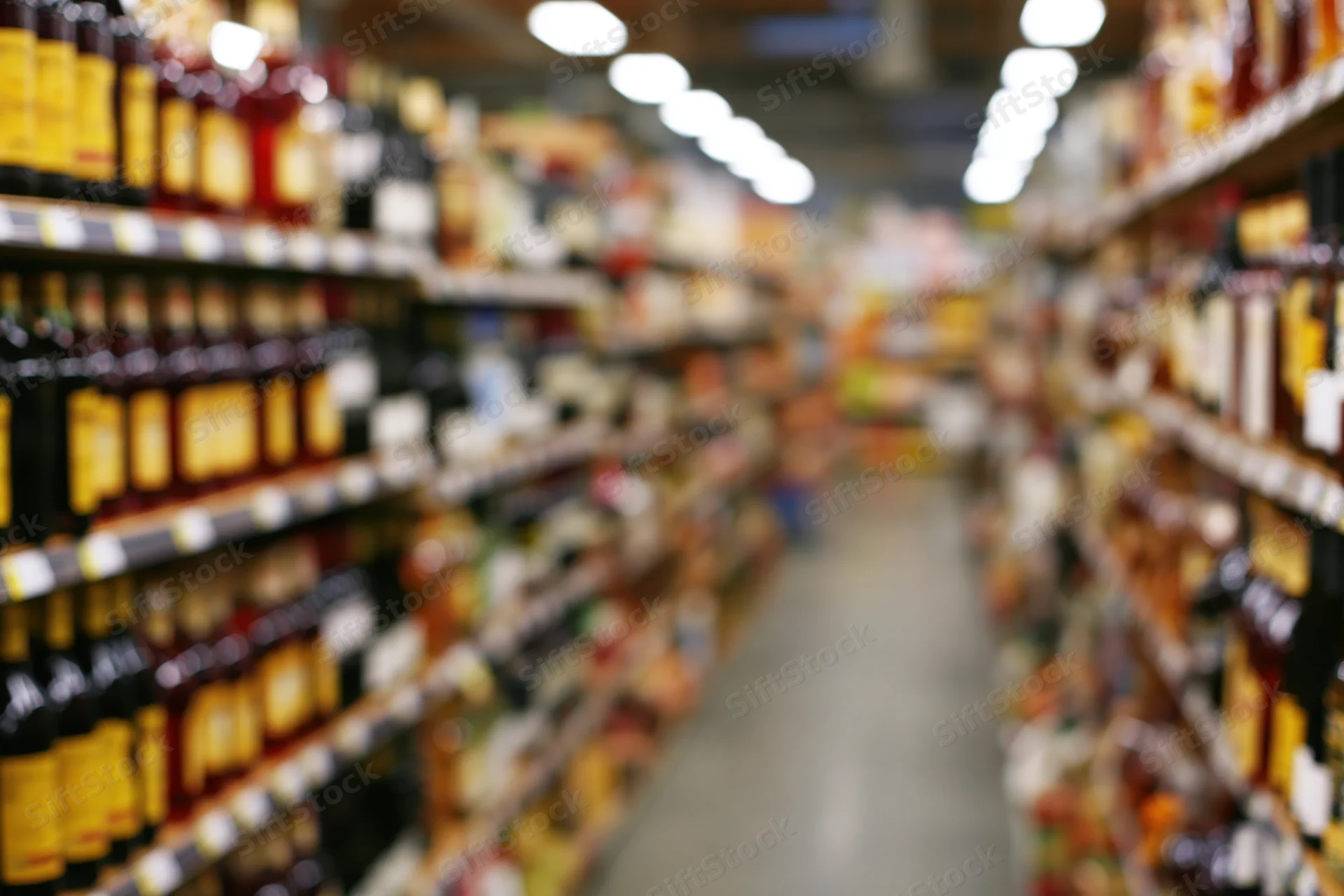 Blurred view of liquor store aisle with tall shelves lined with bottles stretching into the distance