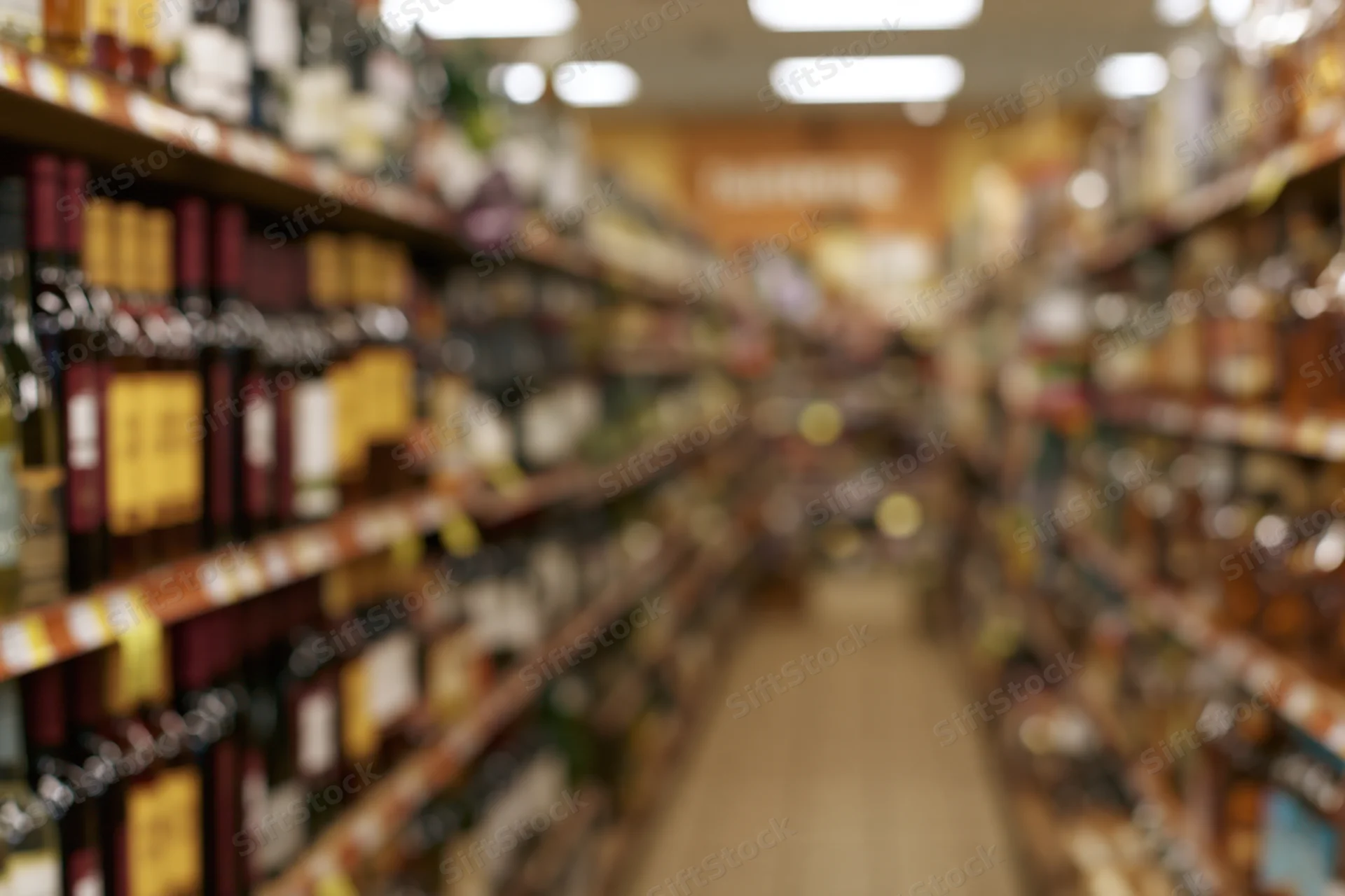 Liquor store aisle with tall shelves filled with bottles stretching into the distance