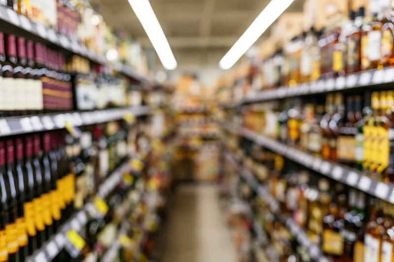 Liquor store aisle with tall shelves filled with bottles stretching into the distance