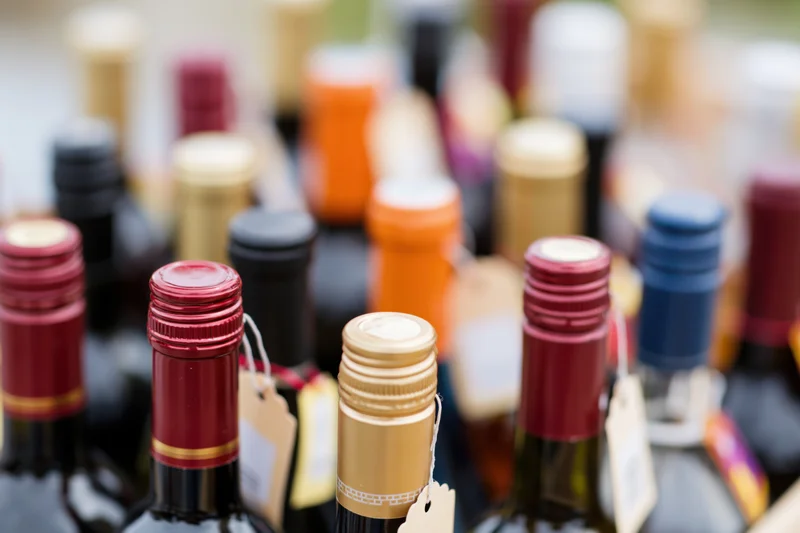 Close-up of assorted wine and liquor bottle tops with tags arranged in rows