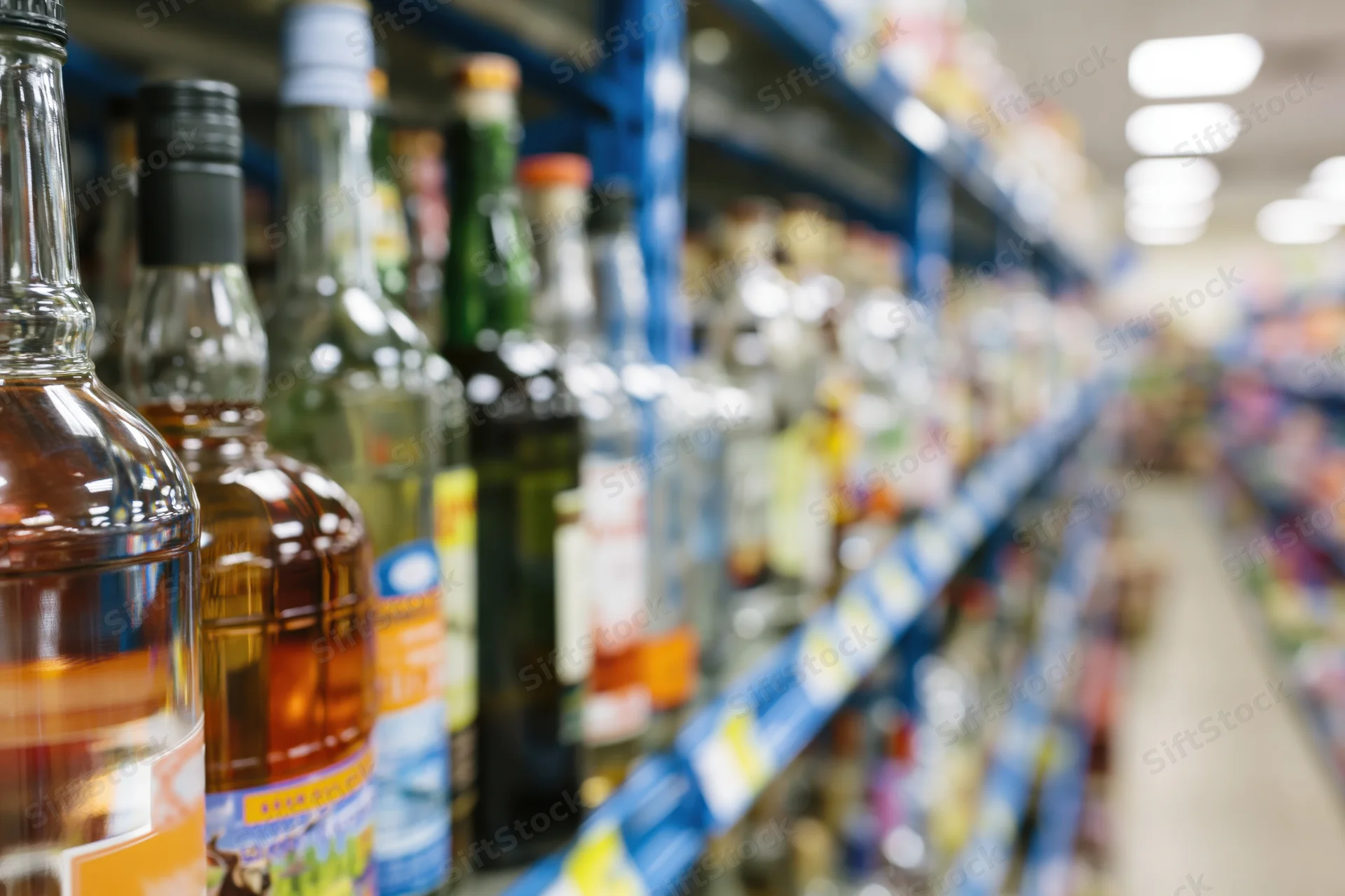 Rows of liquor bottles on blue metal shelves in a supermarket aisle