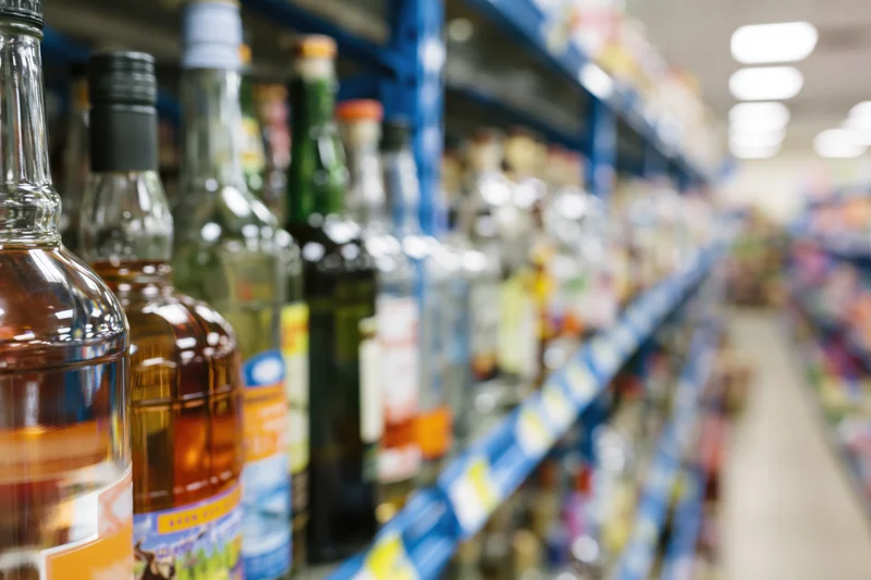Rows of liquor and spirits bottles packed on blue shelves