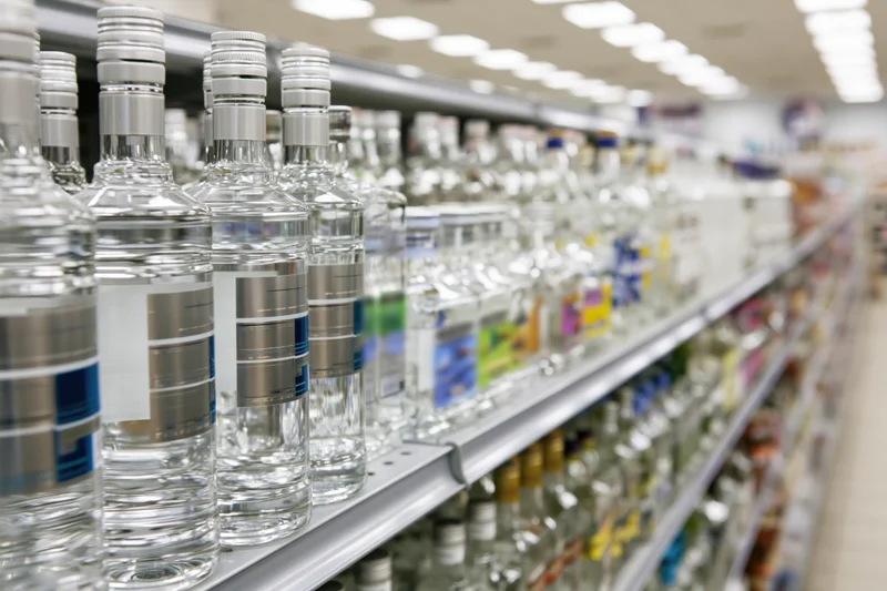 Rows of vodka and spirits bottles on metal shelves in a retail store aisle