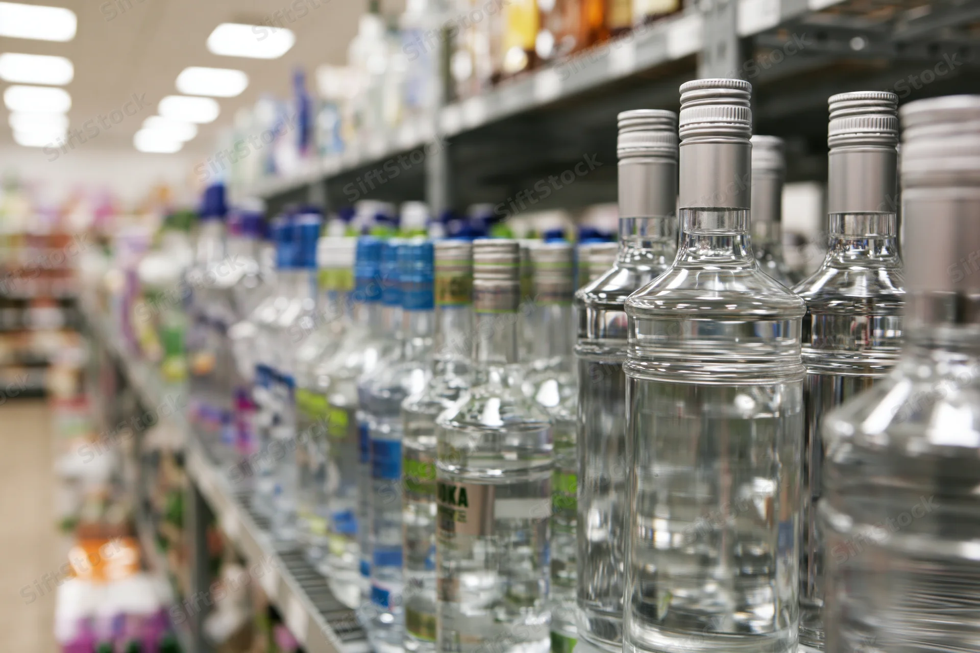 Rows of vodka and spirits bottles on metal shelves in a supermarket aisle