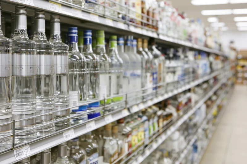 Rows of vodka and spirits bottles on metal shelves in a retail store aisle