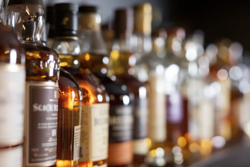 Rows of whisky and spirits bottles lined up on a bar shelf